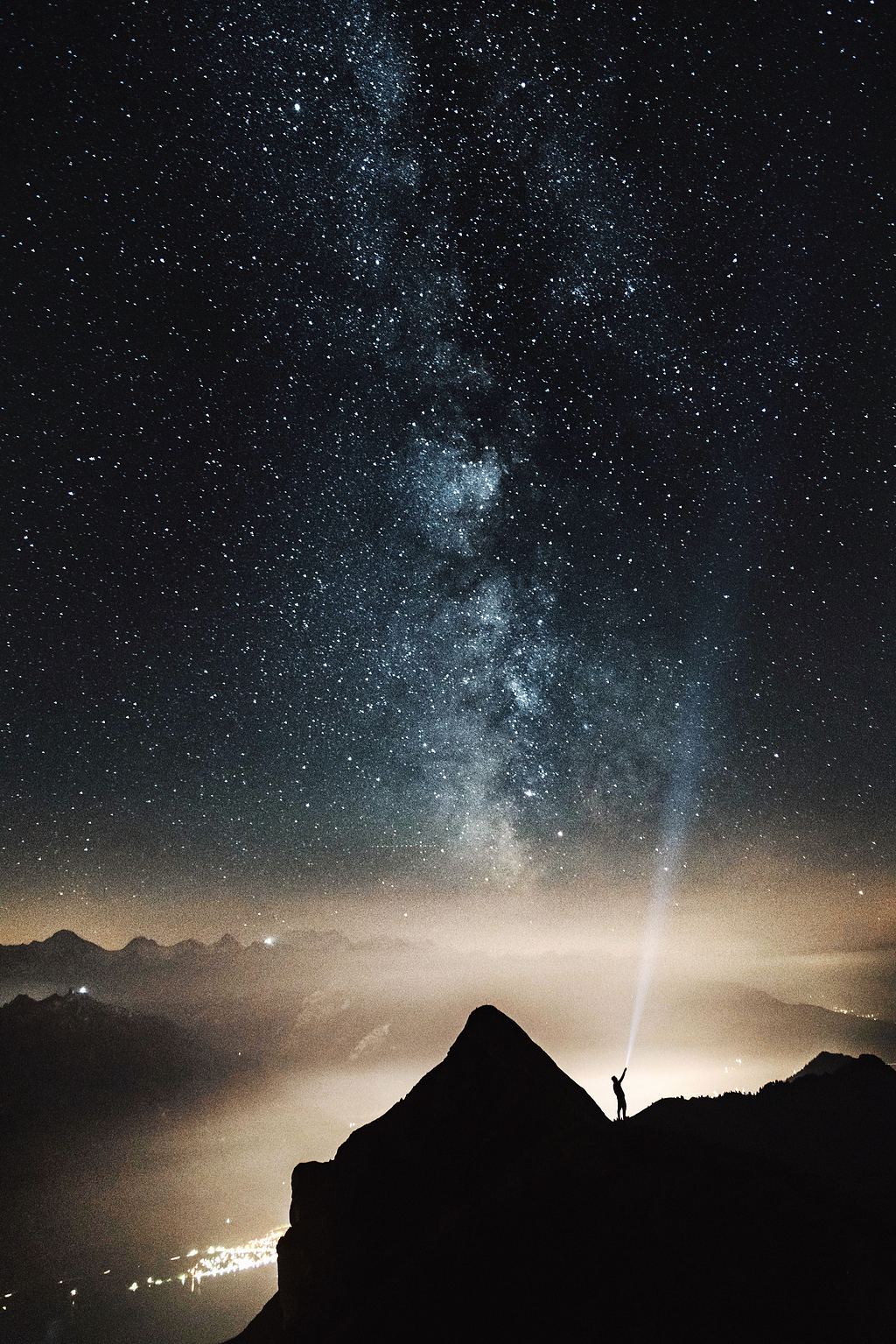 夜晚山顶上人的轮廓,指着满天星星的手电筒