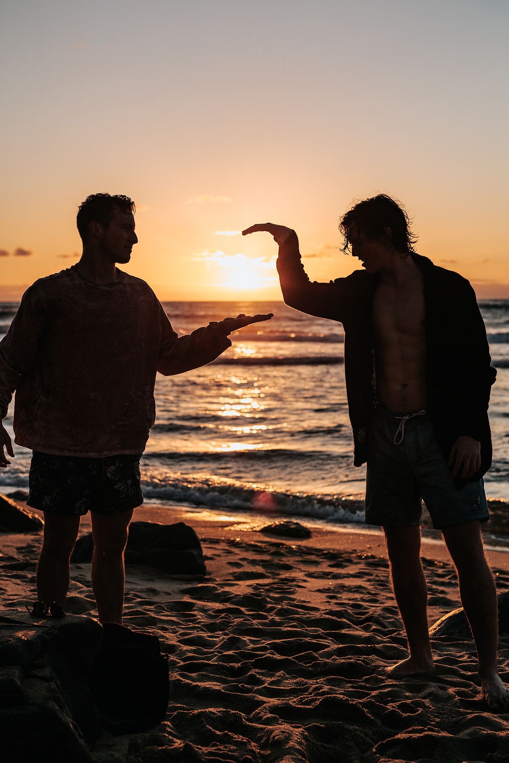 两个人在夕阳附近海滩握手的特写照片