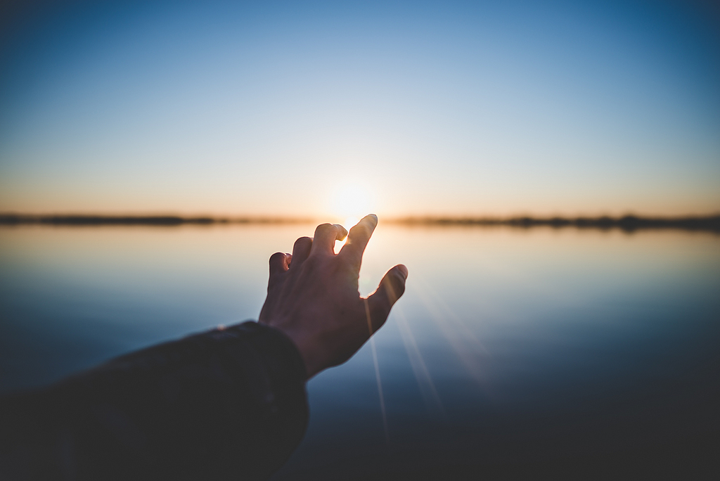 人的手在太阳前的风景摄影