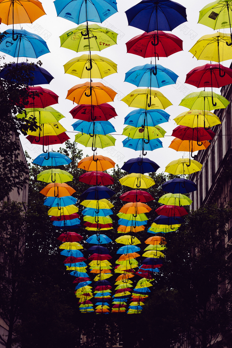 白天在两座白色建筑物之间悬挂的雨伞